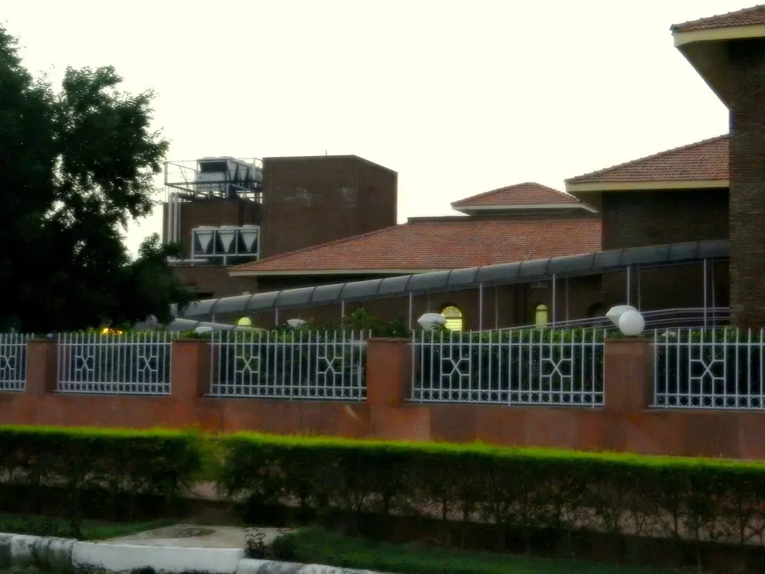 Brick buildings behind a decorative fence on the IGNOU campus.