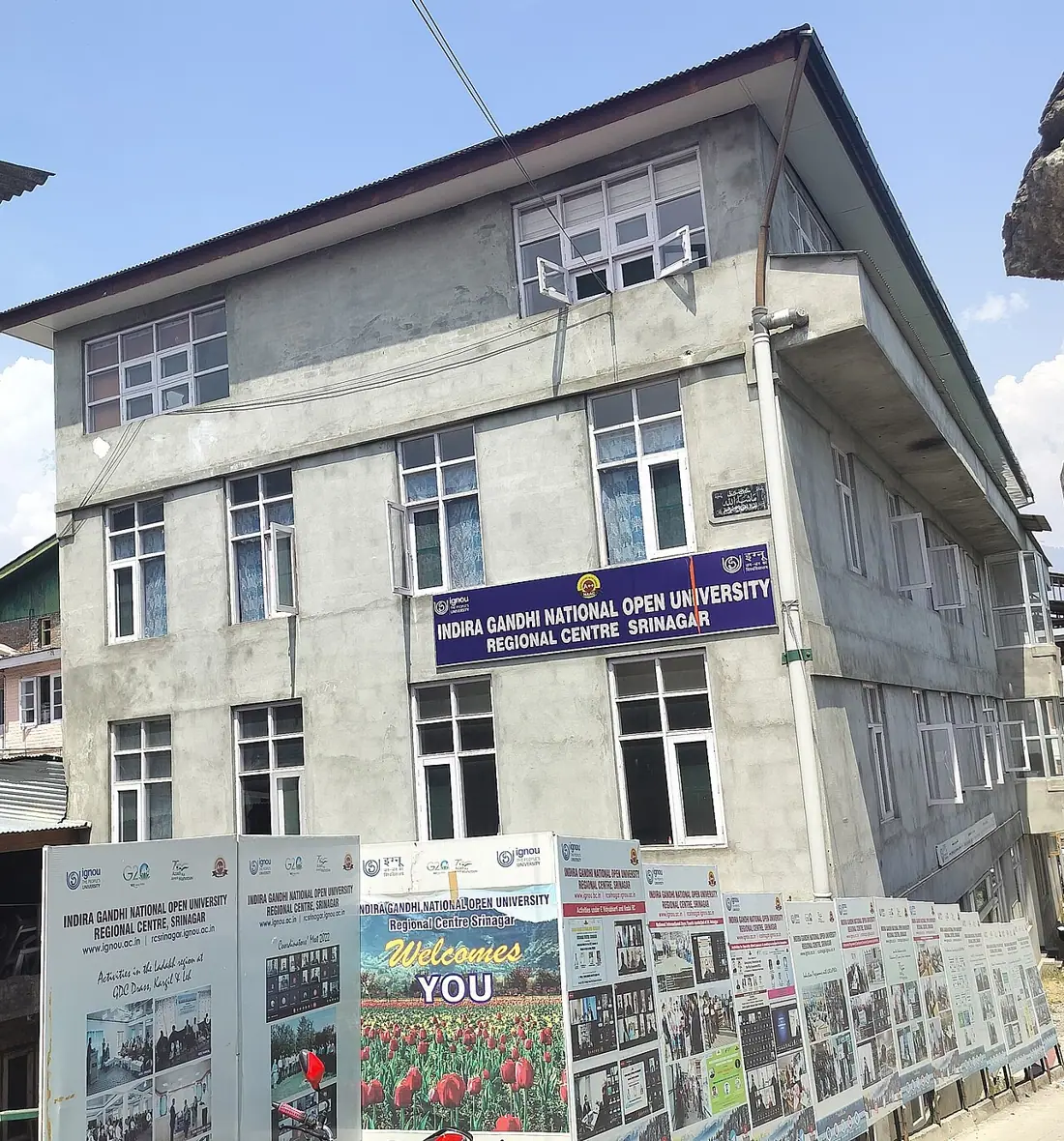 A multi-storey concrete building featuring the IGNOU Regional Centre signboard and promotional posters.
